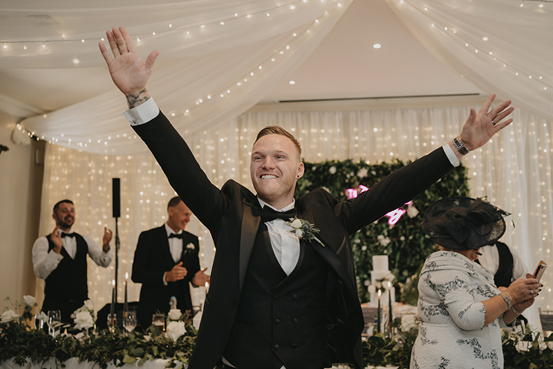 a man in a tuxedo with his arms up